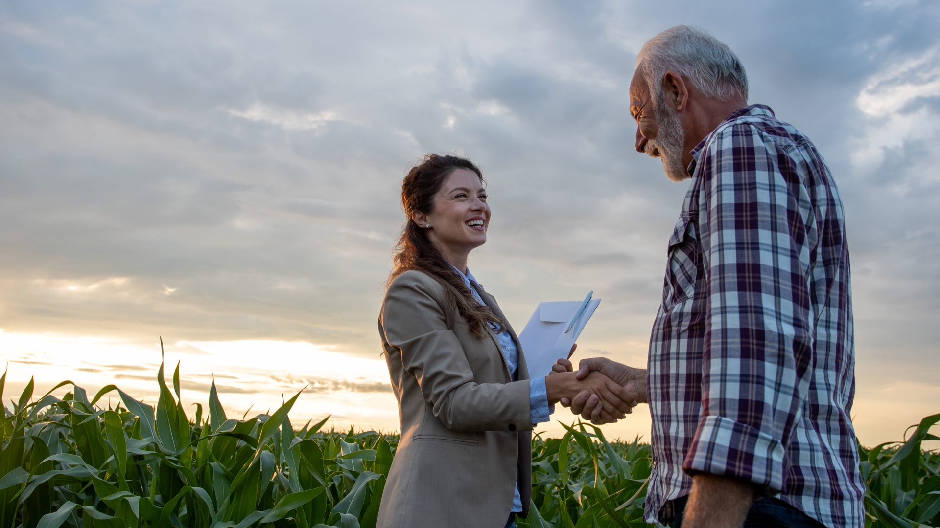 A woman shaking hands with a farmer in a field